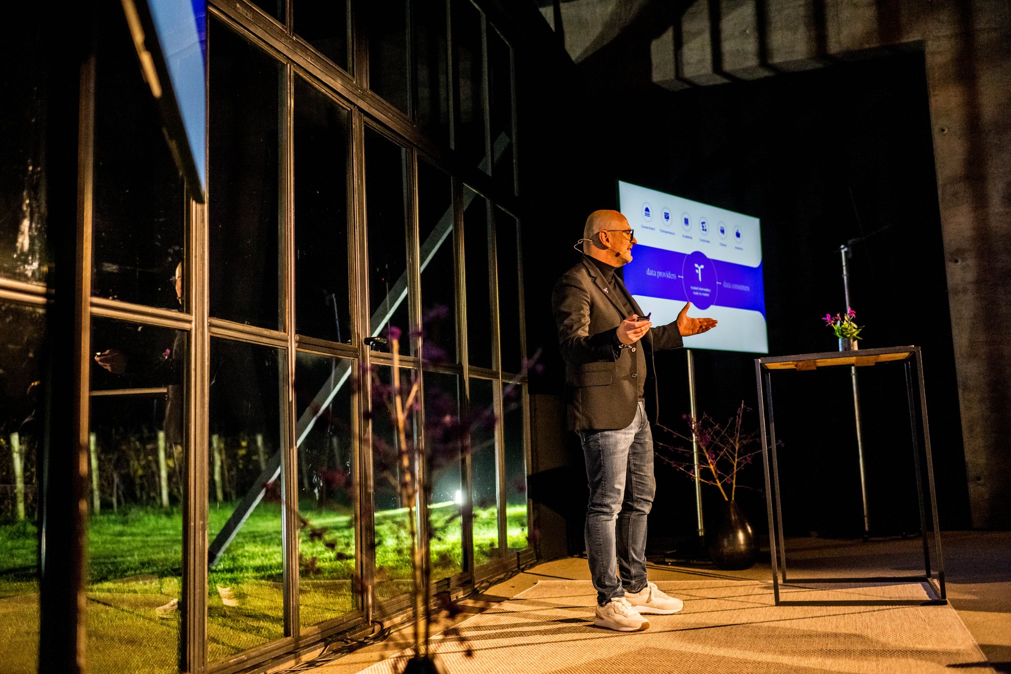A speaker presenting on stage in front of a screen